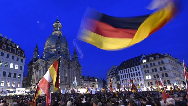 Protestors wave a German flag in front of the Church of Our Lady during a demonstration of PEGIDA (Patriotic Europeans against the Islamization of the West) in Dresden, eastern Germany - Sputnik International