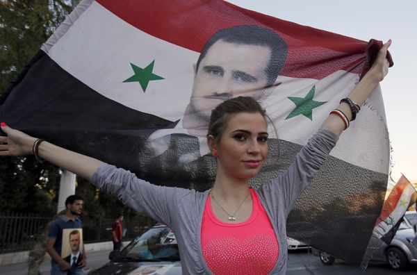 A Syrian girl holds her national flag bearing a portrait of Syria's President Bashar al-Assad - Sputnik International
