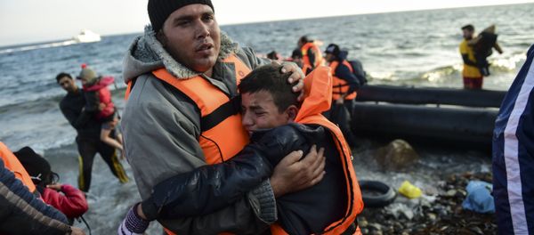Peopl react after arriving on the Greek island of Lesbos along with other migrants and refugees, on November 17, 2015, after crossing the Aegean Sea from Turkey Peopl react after arriving on the Greek island of Lesbos along with other migrants and refugees, on November 17, 2015, after crossing the Aegean Sea from Turkey - Sputnik International