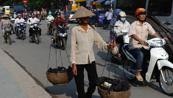 This picture taken on September 10, 2015 shows a migrant worker (C) carrying collected items for recycling walking along a road in downtown Hanoi This picture taken on September 10, 2015 shows a migrant worker (C) carrying collected items for recycling walking along a road in downtown Hanoi - Sputnik International