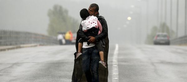 A Syrian refugee kisses his daughter as he walks through a rainstorm towards Greece's border with Macedonia, near the Greek village of Idomeni, September 10, 2015 A Syrian refugee kisses his daughter as he walks through a rainstorm towards Greece's border with Macedonia, near the Greek village of Idomeni, September 10, 2015 - Sputnik International