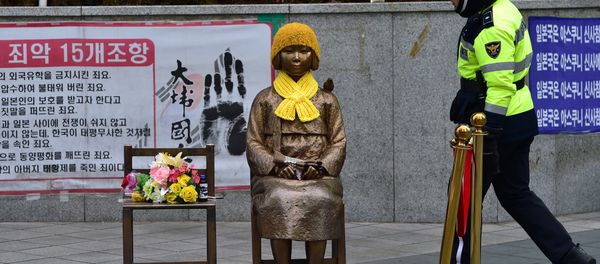 A South Korean policeman walks past a statue (C) of a teenage girl in traditional costume called the peace monument for former comfort women who served as sex slaves for Japanese soldiers during World War II, in front of the Japanese embassy in Seoul on December 29, 2015. - Sputnik International