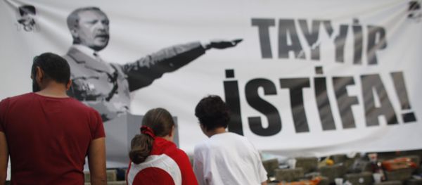 A young protester wearing a Turkish flag stands in front of a banner featuring Turkish Prime Minister Recep Tayyip Erdogan as Adolf Hitler in Gezi park near Taksim square in Istanbul, Friday, June 7, 2013 - Sputnik International