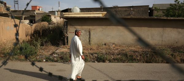 In this Wednesday, May 27, 2015 photo, a resident of Eski Mosul, Iraq is seen through barbed wire while passing the former base of the Islamic State group in the town while it was under the militants' control - Sputnik International
