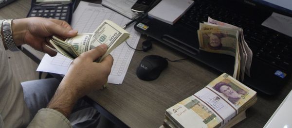 A currency exchange bureau worker counts US dollars, as Iranian bank notes are seen at right with portrait of late revolutionary founder Ayatollah Khomeini. - Sputnik International
