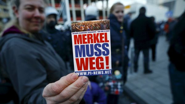 A supporter of the anti-immigration right-wing movement PEGIDA (Patriotic Europeans Against the Islamisation of the West) holds up a sticker for a photo during a demonstration rally in Cologne, Germany January 9, 2016. The sticker reads, Merkel must go!. A supporter of the anti-immigration right-wing movement PEGIDA (Patriotic Europeans Against the Islamisation of the West) holds up a sticker for a photo during a demonstration rally in Cologne, Germany January 9, 2016. The sticker reads, Merkel must go!. - Sputnik International