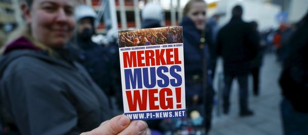 A supporter of the anti-immigration right-wing movement PEGIDA (Patriotic Europeans Against the Islamisation of the West) holds up a sticker for a photo during a demonstration rally in Cologne, Germany January 9, 2016. The sticker reads, Merkel must go!. A supporter of the anti-immigration right-wing movement PEGIDA (Patriotic Europeans Against the Islamisation of the West) holds up a sticker for a photo during a demonstration rally in Cologne, Germany January 9, 2016. The sticker reads, Merkel must go!. - Sputnik International