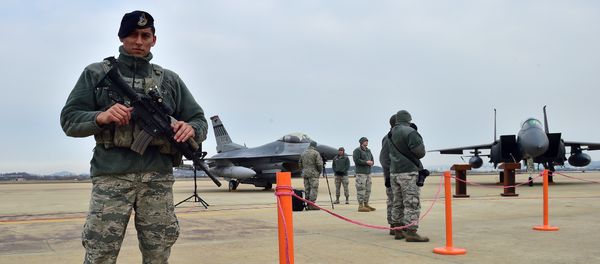 A US soldier (L) stands guard near a US F-16 fighter jet (C) and a South Korea F-15K fighter jet (R) before a press briefing on the flight by a US B-52 Stratofortress over South Korea at the Osan Air Base in Pyeongtaek, south of Seoul, on January 10, 2016 - Sputnik International