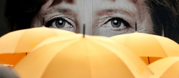 Supporters of the Christian Democratic Union (CDU) hold umbrellas in front of a giant portrait of German Chancellor Angela Merkel during an election campaign event in front of the party's headquarter in Berlin, Germany, Monday, Sept. 16, 2013. - Sputnik International