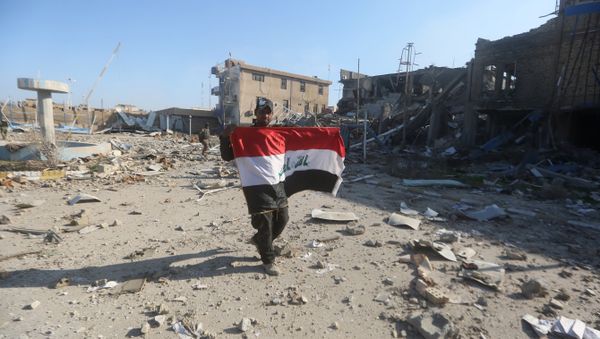 A member of the Iraqi security forces holds his national flag on December 28, 2015 at the heavily damaged government complex after they recaptured the city of Ramadi, the capital of Iraq's Anbar province, about 110 kilometers west of Baghdad, from Islamic States group jihadists - Sputnik International