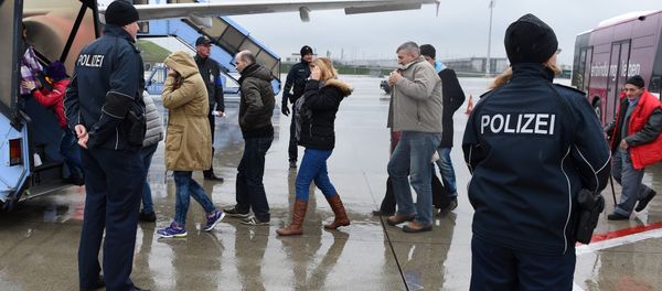 Police officers escort rejected refugees who are boarding an aircraft at the airfield of the Franz-Josef-Strauss airport in Munich, southern Germany, on December 9, 2015, as the plane brings rejected asylum seekers back to their country - Sputnik International