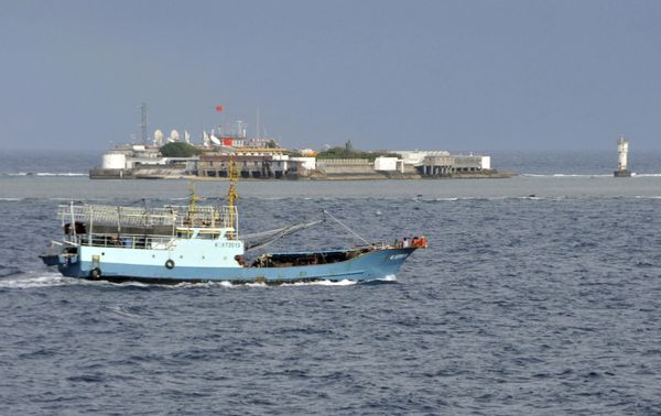 Chinese fishing vessel sails by Fiery Cross Reef, background, also known as Yongshu Reef by the Chinese, of the Spratly Islands in the South China Sea - Sputnik International