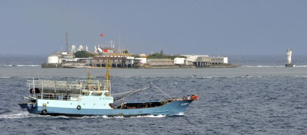 Chinese fishing vessel sails by Fiery Cross Reef, background, also known as Yongshu Reef by the Chinese, of the Spratly Islands in South China Sea Chinese fishing vessel sails by Fiery Cross Reef, background, also known as Yongshu Reef by the Chinese, of the Spratly Islands in South China Sea - Sputnik International
