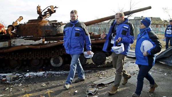 Deputy Chief of the OSCE's Special Monitoring Mission to Ukraine Alexander Hug (L), with members of the mission, walks past a burnt tank as he inspects an area between DPR forces and Ukrainian government troops in the village of Kominternove north-east of the port city of Mariupol, Ukraine, January 15, 2016 - Sputnik International