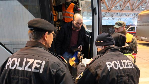 Austrian police officer check the identification documents of migrants before allowing them to get out a bus from Slovenia to cross the border from Slovenia into Austria, at a checkpoint at the Karawanks tunnel near Villach, Austria, Wednesday, Jan. 13, 2016 - Sputnik International