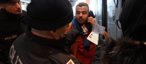 Austrian police officer check the identification documents of migrants before allowing them to get out a bus from Slovenia to cross the border from Slovenia into Austria, at a checkpoint at the Karawanks tunnel near Villach, Austria, Wednesday, Jan. 13, 2016 - Sputnik International