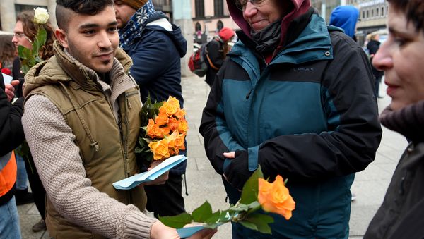 Refugees from Syria present flowers to passers-by as they demonstrate against violence near the Cologne main train station in Cologne, western Germany on January 16, 2016, where hundreds of women were groped and robbed in a throng of mostly Arab and North African men during New Year's festivities Refugees from Syria present flowers to passers-by as they demonstrate against violence near the Cologne main train station in Cologne, western Germany on January 16, 2016, where hundreds of women were groped and robbed in a throng of mostly Arab and North African men during New Year's festivities - Sputnik International