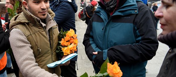 Refugees from Syria present flowers to passers-by as they demonstrate against violence near the Cologne main train station in Cologne, western Germany on January 16, 2016, where hundreds of women were groped and robbed in a throng of mostly Arab and North African men during New Year's festivities - Sputnik International