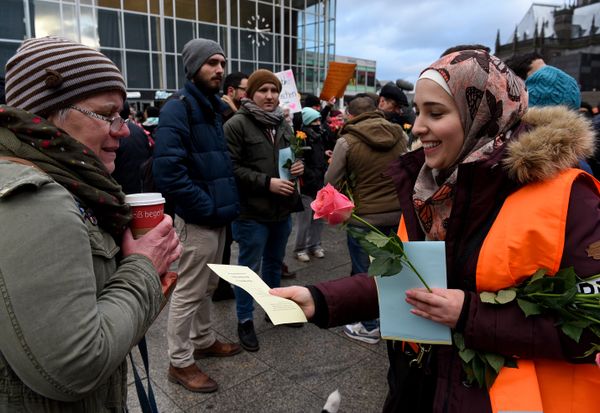 Refugees from Syria present flowers to passers-by as they demonstrate against violence near the Cologne main train station in Cologne, western Germany on January 16, 2016, where hundreds of women were groped and robbed in a throng of mostly Arab and North African men during New Year's festivities - Sputnik International