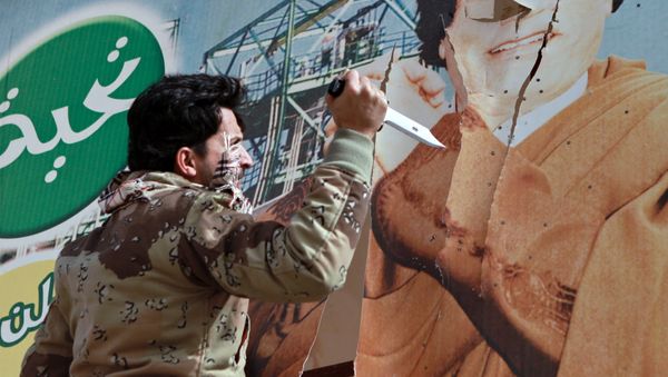 Libyan opposition supporter uses knife to cut a poster of Muammar Gaddafi in the captured rebel town of Ras Lanuf in the east of the country Libyan opposition supporter uses knife to cut a poster of Muammar Gaddafi in the captured rebel town of Ras Lanuf in the east of the country - Sputnik International
