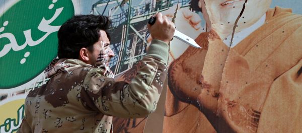Libyan opposition supporter uses knife to cut a poster of Muammar Gaddafi in the captured rebel town of Ras Lanuf in the east of the country Libyan opposition supporter uses knife to cut a poster of Muammar Gaddafi in the captured rebel town of Ras Lanuf in the east of the country - Sputnik International