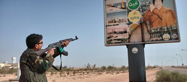 An armed supporter of the Libyan opposition shoots a machine gun at a poster with the image of Muhammar Gaddafi in the captured rebel town of Ras-Lanuf in the east of the country - Sputnik International