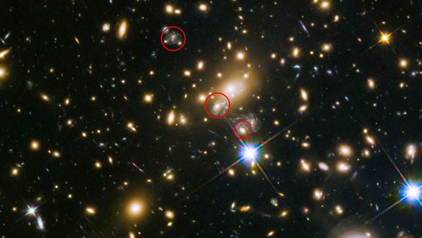 This image shows the appearances of the Refsdal supernova. The uppermost circle shows the position of the supernova as it could have been seen in 1998. The lowermost circle shows the galaxy which lensed the supernova four time — a discovery made in late 2014. The middle circle shows the latest position of the reappearing supernova in 2015. - Sputnik International