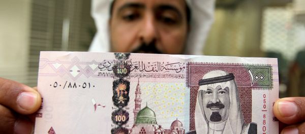 A Saudi banker displays the new one hundred riyal banknote bearing the portrait of Saudi King Abdullah bin Abdul Aziz al-Saud at a bank in Riyadh, 05 June 2007 A Saudi banker displays the new one hundred riyal banknote bearing the portrait of Saudi King Abdullah bin Abdul Aziz al-Saud at a bank in Riyadh, 05 June 2007 - Sputnik International