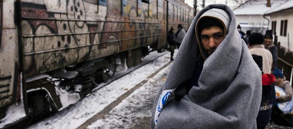 A migrant wrapped in a blanket to keep warm, waits with other migrants and refugees to board a train heading to the border with Croatia at the train station in Presevo, on January 19, 2016, after crossing the Macedonian border into Serbia A migrant wrapped in a blanket to keep warm, waits with other migrants and refugees to board a train heading to the border with Croatia at the train station in Presevo, on January 19, 2016, after crossing the Macedonian border into Serbia - Sputnik International