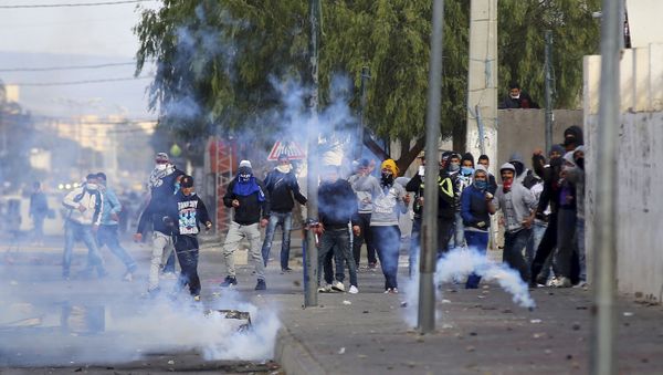 Protesters throwing rocks are seen amid tear gas fired by police in Kasserine, Tunisia - Sputnik International