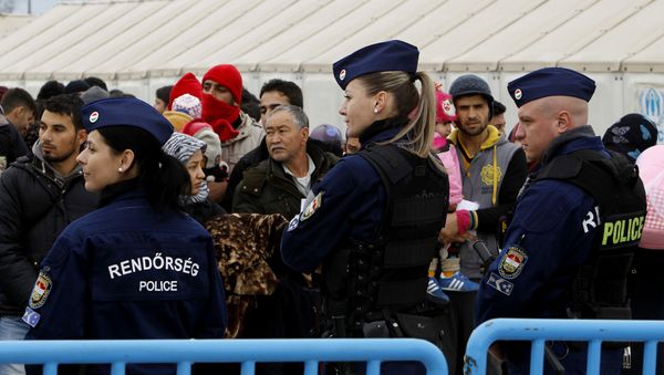 Hungarian police officers keep order as migrants wait to board a train towards Serbia. Hungarian police officers keep order as migrants wait to board a train towards Serbia. - Sputnik International