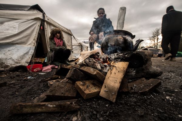 Migrants get warm around a brazier in the migrants camp of Grande-Synthe, near Dunkirk - Sputnik International