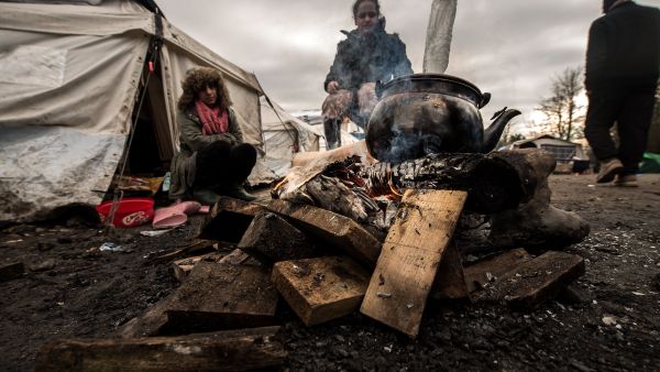 Migrants get warm around a brazier in the migrants camp of Grande-Synthe, near Dunkirk - Sputnik International