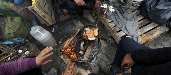 Migrants prepare their food outside shelters in a muddy field called the Grande-Synthe jungle, near Dunkirk, northern France - Sputnik International
