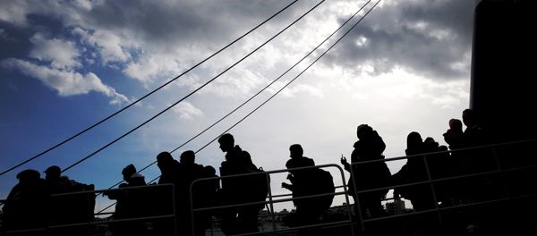Refugees and migrants are silhouetted as they arrive aboard the passenger ferry Ariadne at the port of Piraeus, near Athens, Greece, January 4, 2016. - Sputnik International