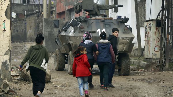 Backdropped by a Turkish forces armoured personnel carrier, residents walk around after the 24-hour curfew was lifted, in the mostly-Kurdish town of Silopi, in southeastern Turkey, near the border with Iraq, Tuesday, Jan. 19, 2016 Backdropped by a Turkish forces armoured personnel carrier, residents walk around after the 24-hour curfew was lifted, in the mostly-Kurdish town of Silopi, in southeastern Turkey, near the border with Iraq, Tuesday, Jan. 19, 2016 - Sputnik International
