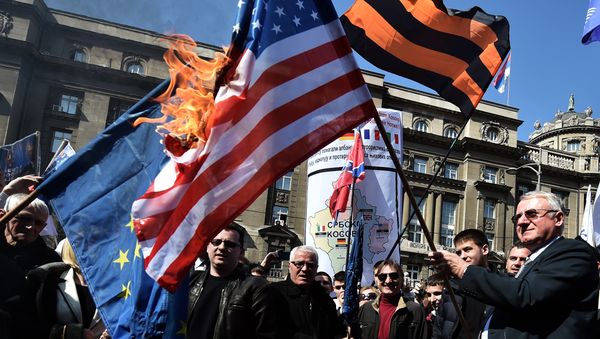 Serbian nationalist politician Vojislav Seselj (R) surrounded by his supporters holds a burning NATO flag during an anti-government rally on March 24, 2015, in front of the building of the former federal Interior Ministry in Belgrade Serbian nationalist politician Vojislav Seselj (R) surrounded by his supporters holds a burning NATO flag during an anti-government rally on March 24, 2015, in front of the building of the former federal Interior Ministry in Belgrade - Sputnik International