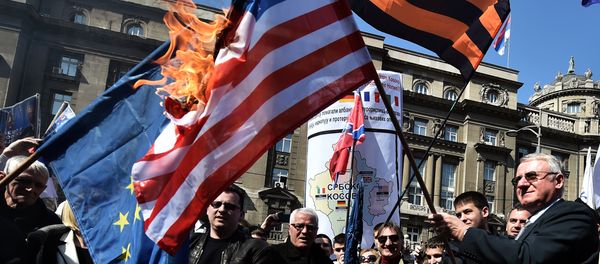 Serbian nationalist politician Vojislav Seselj (R) surrounded by his supporters holds a burning NATO flag during an anti-government rally on March 24, 2015, in front of the building of the former federal Interior Ministry in Belgrade Serbian nationalist politician Vojislav Seselj (R) surrounded by his supporters holds a burning NATO flag during an anti-government rally on March 24, 2015, in front of the building of the former federal Interior Ministry in Belgrade - Sputnik International