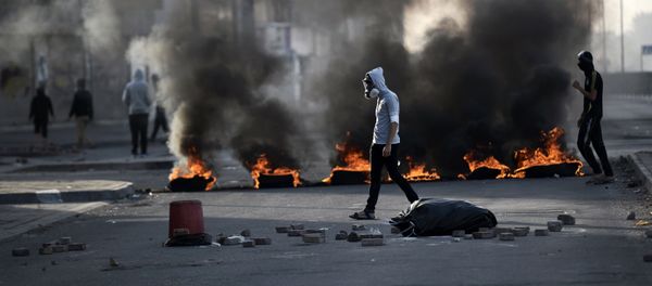 Bahraini protesters walk past burning tyres during clashes with riot police in the village of Sitra, south of the capital Manama, on January 8, 2016, following a protest against the execution of prominent Shiite Muslim cleric Nimr al-Nimr by Saudi authorities - Sputnik International