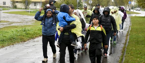 Refugees walk through the pouring rain from a public transport centre to the Lappia-building refugee reception centre in Tornio, northwestern Finland, on September 2015 - Sputnik International