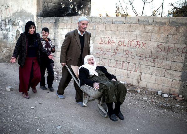 A man wheels a sick person in a wheelbarrow through the barricades set up by the militants of the Kurdistan Workers' Party, or PKK, in Nusaybin, Turkey, Thursday, Dec. 24, 2015.  - Sputnik International