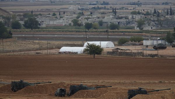 Men watch fighting across the border in Kobani from a hilltop on the outskirts of Suruc, Turkey, backdropped by Turkish army artillery positions near the Turkey-Syria border, Sunday, Oct. 26, 2014 Men watch fighting across the border in Kobani from a hilltop on the outskirts of Suruc, Turkey, backdropped by Turkish army artillery positions near the Turkey-Syria border, Sunday, Oct. 26, 2014 - Sputnik International