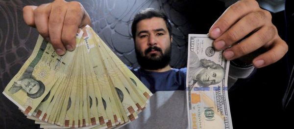 A money changer poses for the camera with a US dollar (R) and the amount being given when converting it into Iranian rials (L), at a currency exchange shop in Tehran's business district, Iran, in this January 20, 2016 file photo A money changer poses for the camera with a US dollar (R) and the amount being given when converting it into Iranian rials (L), at a currency exchange shop in Tehran's business district, Iran, in this January 20, 2016 file photo - Sputnik International