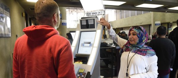 Contractor Sabira Dewji, right, helps a pedestrian crossing from Mexico into the United States at the Otay Mesa Port of Entry have his facial features and eyes scanned at a biometric kiosk Thursday, Dec. 10, 2015, in San Diego Contractor Sabira Dewji, right, helps a pedestrian crossing from Mexico into the United States at the Otay Mesa Port of Entry have his facial features and eyes scanned at a biometric kiosk Thursday, Dec. 10, 2015, in San Diego - Sputnik International