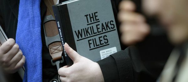 A supporter of WikiLeaks founder julian Assange holds a copy of The WikiLeaks Files outside the Ecuadorian embassy in central London, Britain February 5, 2016 - Sputnik International
