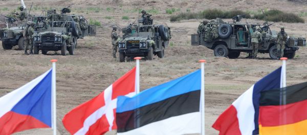 In this June 18, 2015,file photo flags wave in front of soldiers who take positions with their army vehicles during the NATO Noble Jump exercise on a training range near Swietoszow Zagan, Poland In this June 18, 2015,file photo flags wave in front of soldiers who take positions with their army vehicles during the NATO Noble Jump exercise on a training range near Swietoszow Zagan, Poland - Sputnik International