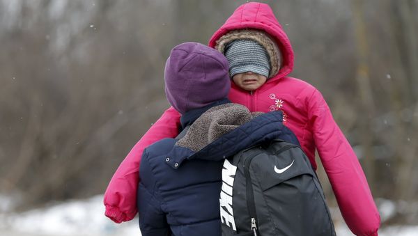 A migrant carries a child as they walk through a frozen field after crossing the border from Macedonia, near the village of Miratovac, Serbia, January 18, 2016. A migrant carries a child as they walk through a frozen field after crossing the border from Macedonia, near the village of Miratovac, Serbia, January 18, 2016. - Sputnik International