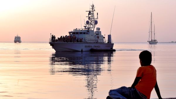 A migrant boy watches an Italian Frontex vessel loaded by intercepted migrants arriving to the port of Kos on August 16, 2015, on the island of Kos. A migrant boy watches an Italian Frontex vessel loaded by intercepted migrants arriving to the port of Kos on August 16, 2015, on the island of Kos. - Sputnik International