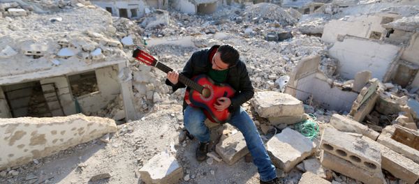 Shehab, a 23-year-old Syrian, practices the guitar amidst the rubble of buildings in the northern Syrian city of Aleppo on December 11, 2015. - Sputnik International