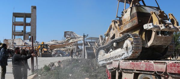 A bulldozer is unloaded from a truck as people gather around the rubble of a hospital supported by Doctors Without Borders (MSF) near Maaret al-Numan, in Syria's northern province of Idlib, on February 15, 2016 A bulldozer is unloaded from a truck as people gather around the rubble of a hospital supported by Doctors Without Borders (MSF) near Maaret al-Numan, in Syria's northern province of Idlib, on February 15, 2016 - Sputnik International